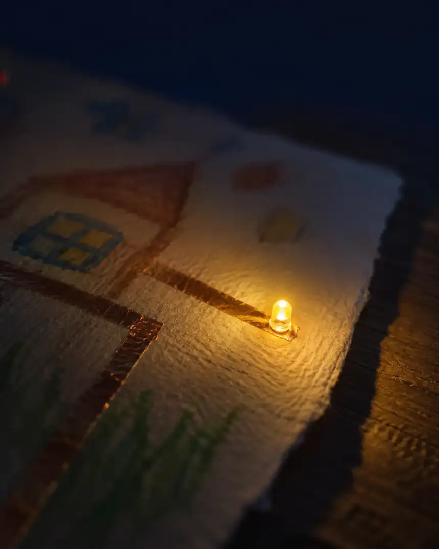 Casa desenhada em papel com fita de cobre e uma pequena luz acesa